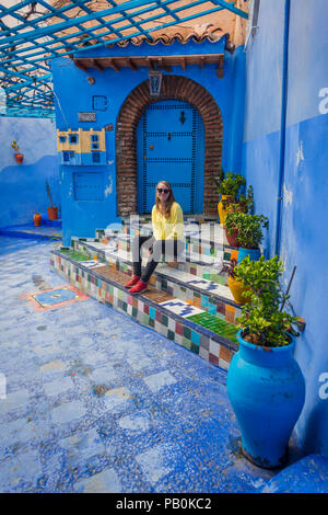 Junge Frau in der Altstadt befindet sich auf einer Treppe, blaues Haus Wände, Medina von Meknes, Chaouen, Tangier-Tétouan Stockfoto