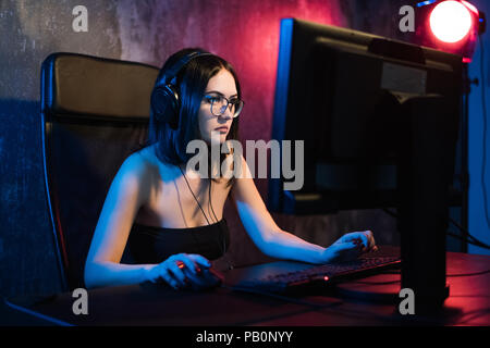 Professionelle girl Gamer spielt in MMORPG oder Strategie Spiel auf Ihrem Computer. Sie ist die Teilnahme an Online Cyber Games Turnier, spielt zu Hause oder im Internetcafé. Sie trägt Gaming Headset Stockfoto