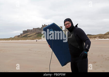 Mann mit einem Bodyboard auf Bamburgh Beach in Northumberland, England. Er ist es, den Teilnehmenden die der Nördlichen Bootcamp, ein Wohn-Boot Camp. Stockfoto