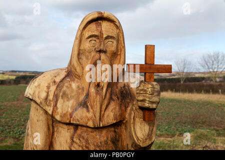 Geschnitzte Holzfigur, die St Cuthbert auf St Cuthbert's Way darstellt, einem Fußweg in der Landschaft von Northumberland, England. Stockfoto