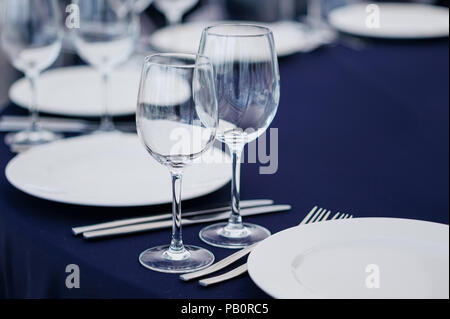 Anordnung der leeren elegante Geschirr und Besteck mit Weingläsern auf Blau Tischdecke Stockfoto