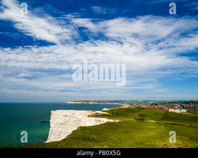 Menschen, die an einem sonnigen Frühlingstag auf Seaford Head, East Sussex, Großbritannien, mit den Städten Seaford und Newhaven im Hintergrund spazieren gehen. Stockfoto