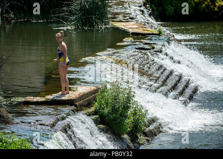 Eine Frau kühlt sich ab auf dem Wehr an Bathampton Mühle am Fluss Avon in der Nähe von Bath in Somerset, da die Temperaturen weiter über das Vereinigte Königreich zu erheben. Stockfoto