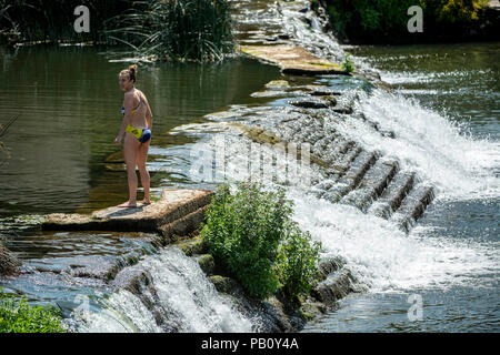 Eine Frau kühlt sich ab auf dem Wehr an Bathampton Mühle am Fluss Avon in der Nähe von Bath in Somerset, da die Temperaturen weiter über das Vereinigte Königreich zu erheben. Stockfoto