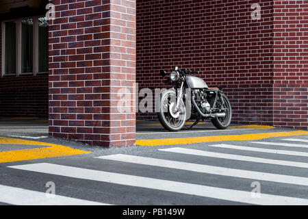 Oldtimer Motorrad Parkplatz in der Nähe der Mauer der industriellen Gebäude. Alles ist bereit für Spaß nach einem harten Tag im Büro. Geschäftsmann Stadt hipste Stockfoto