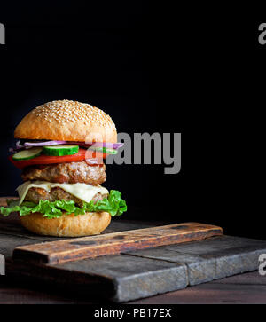 Große Burger mit zwei gebratene Koteletts, Käse und Gemüse in einer Runde Weizenmehl bun, Kopie Raum Stockfoto