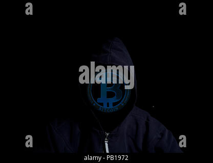 Anonyme Crypto Hacker in der Motorhaube mit bitcoin auf schwarzem Hintergrund Stockfoto