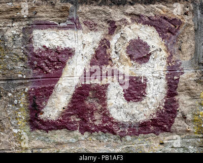 Nummer 79 auf einer Steinmauer in Edinburgh, Schottland, Vereinigten Königreich, Lila Hintergrund mit weißen Nummern gestrichen. Stockfoto