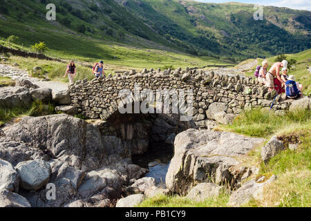 Wanderer Wandern am Anschluss über Stockley Brücke in Lake District National Park im Sommer. Seathwaite, Cumbria, England, Großbritannien, Großbritannien Stockfoto