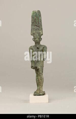 Amun. Abmessungen: H 15,7 cm (6 3/16 in.); W. 3.3 cm (1 5/16 in.); D.5.2 cm (2 1/16 in.). Datum: 664-30 v. Chr.. Amun war einer der am meisten gefeierten Gottheiten Ägyptens, als universelle, kosmische Gott und häufig der König der Götter genannt verehrt. Kupferlegierung, er ist fast immer gezeigt, wie hier, in anthropomorphen Form trägt einen kurzen Kilt und einem großen Doppelbett Federkrone mit einer Sonnenscheibe, die Anspielung auf seine Solare und kosmische Aspekte, einschließlich seiner Verschmelzung mit dem Sonnengott Re. Weitere Ausarbeitungen auf Dieser statuette gehören ein breites Halsband und Armbänder. Seine rechte Hand ist für die att gesockelt Stockfoto