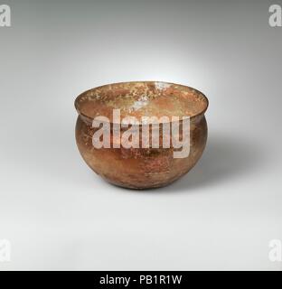 Glasschale. Kultur: Roman. Abmessungen: H.: 2 3/8 in. (6 cm) Durchm.: 3 7/8 x 3 7/8 in. (9,8 x 9,8 cm). Datum: 1. Jh. N.CHR.. Farblos mit blauen Grðnstich geklopft, uneben, vertikale Rim; kurzer Hals, konkav konvex gebogenen Seiten unten konkav. Dekoration von vier parallele Bänder von Rad - abgenutzte Linien auf Körper, aslant an RIM. Intakt, außer einer sehr kleinen Chip in Rim; viele Pinprick blasen; tiefe Rillen, Mattieren, und irisierenden Bewitterung im Außenbereich; cremig Braun überstehen auf Interieur. Museum: Metropolitan Museum of Art, New York, USA. Stockfoto