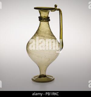 Glaskanne. Kultur: Roman. Abmessungen: H. 9 3/4 in. (24,8 cm). Datum: 4.Jahrhundert N.CHR.. Transluzente Olive grün; Griff und einem Trail in der gleichen Farbe, eine andere Spur in den tiefen Türkisblau. Auch als horizontale Rim mit abgerundeten Lippe; abfackeln Mund und kurze zylindrische Hals, bauchigen, doppelkonische Körper, dann verjüngt sich hohlen Stamm; große gespreizter Fuß mit dicken röhrenförmige Kante durch Falten; konkaver Boden mit kleinen Kick am mittleren und großen pontil Narbe; Griff der Stange mit der Körper an der Stelle des größten Durchmessers zu Seite, senkrecht nach oben gezogen, gedreht in Mit eingeklemmt über rim Falten, und verstummte unter Rim. Bod Stockfoto