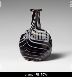 Glas Mosaik Parfüm Flasche. Kultur: Roman. Abmessungen: Durchm.: 4. (10,2 cm). Datum: 1. Halbjahr 1. Jh. N.CHR.. Transluzente tiefe Kobaltblau, mit durchscheinenden Honig braun, opak Weiße, opake Hellblau und opak Gelb Trails. Auch abgerundete, Rim, zylindrische Hals, leicht nach unten erweitert, mit feinen Gedankenstrich um Base; kugelförmigen Körper; konkave Unterseite. Gestreifte Mosaik Muster der angewandten Wanderwege rund auf blauem Grund gewickelt und dann nachgerüstet in vier Anschläge, abwechselnd nach oben und unten, in einen breiten Feder Muster. Gebrochen und repariert, mit einem großen Chip in Rim, und eine Bohrung ein Stockfoto