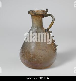 Glaskanne. Kultur: Roman. Abmessungen: 3 5/8 in. (9,3 cm) Andere: 2 7/16 in. (6.2 cm) Durchm. Von rim: 1 1/16-in. (2,7 cm). Datum: 1.-2. Jh. N.CHR.. Klein, Man- Kanne Translucent Hellblau grün; in der gleichen Farbe. Rim ausgeklappt, nach unten und oben, mit vertikalen abgerundete Lippe oben Mund; kurz zylindrischen Hals; konischen Körper in zu flachen base; Handstück als lange vertikale Pad zu Körper, herausgezogen und rund, und schleppte auf Hals und äußeren Rand der Felge mit vertikalen werkzeuggestützte Daumen oben geschwungen. Dekoration von vier horizontale Projektion gedrückt Flossen auf Pad unten. Intakt Stockfoto
