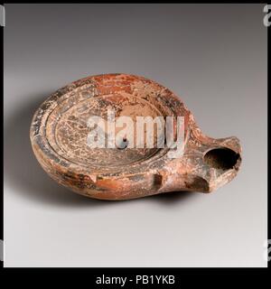 Terrakotta Öllampe. Kultur: Roman, der Zyprischen. Abmessungen: Insgesamt: 1 x 3 1/2 in. (2,5 x 8,9 cm). Schimmel gebildet. Diskus: Plain, konkav Bowl mit zentralen Einfüllöffnung und ein Band von konzentrischen Linien und Nuten in Richtung Rand. Voluten flankierende Düse. Innerhalb beeindruckt Base Ring, leicht konkav, Basis, mit einem zentralen angehobenen Buchstaben: W (oder 4-bar-Sigma). Komplette, außer für die kleine Pause und Verlust auf der Vorder- und Unterseite der Düse. Museum: Metropolitan Museum of Art, New York, USA. Stockfoto