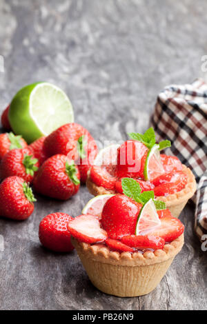 Eierstich Torten mit frischen Erdbeeren und Kalk auf hölzernen Tisch Stockfoto