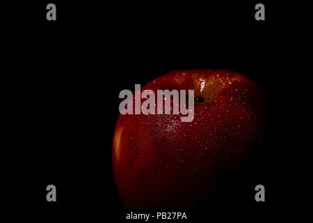 Roter Apfel mit Wassertropfen auf schwarzem Hintergrund Stockfoto