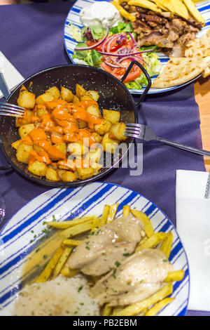 Lemon Chicken mit hausgemachten Pommes frites, Patatas Bravas (Spanische Bratkartoffeln) und Hähnchen Gyros mit hausgemachten Pommes und Salat. Stockfoto