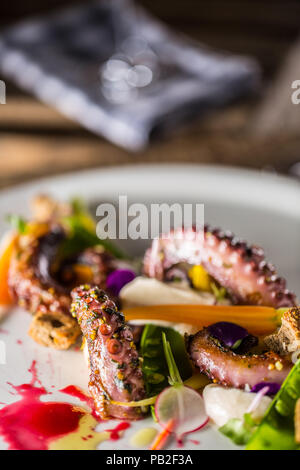 Octopus mit Gemüse Salat auf weiße Platte mit Aperitif. Kulinarische Servieren der Mahlzeiten in den Restaurants. Stockfoto