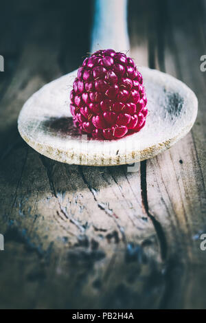 Eine Himbeere auf einem Löffel aus Holz Stockfoto