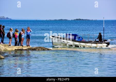 Studenten in der Warteschlange für die Bootsfahrt zu den St Michael Berg, Karrek Loos yn Koos, Marazion, Cornwall, England, Großbritannien Stockfoto