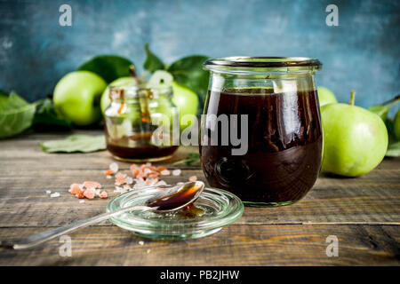 Home Warme dunkle gesalzen classic Karamell-sauce, mit grünen Äpfeln, Holz- und dunkelblauen Hintergrund, Stockfoto