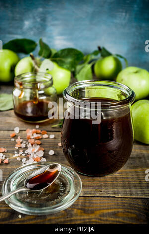 Home Warme dunkle gesalzen classic Karamell-sauce, mit grünen Äpfeln, Holz- und dunkelblauen Hintergrund, Stockfoto