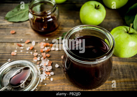 Home Warme dunkle gesalzen classic Karamell-sauce, mit grünen Äpfeln, Holz- und dunkelblauen Hintergrund, Stockfoto