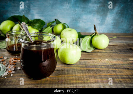 Home Warme dunkle gesalzen classic Karamell-sauce, mit grünen Äpfeln, Holz- und dunkelblauen Hintergrund, Stockfoto