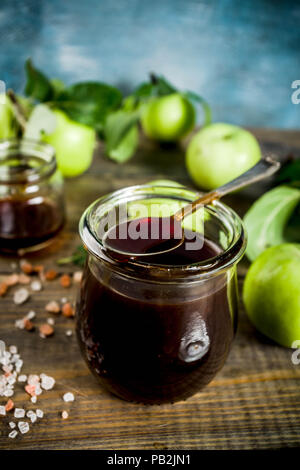 Home Warme dunkle gesalzen classic Karamell-sauce, mit grünen Äpfeln, Holz- und dunkelblauen Hintergrund, Stockfoto