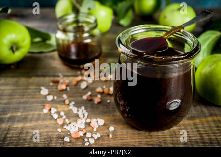 Home Warme dunkle gesalzen classic Karamell-sauce, mit grünen Äpfeln, Holz- und dunkelblauen Hintergrund, Stockfoto