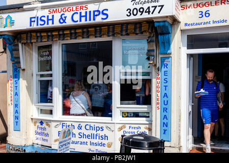 Verläßt der Mann eine traditionelle Fisch und Chip Shop mit einem Kasten von Fish und Chips, Rottingdean, Sussex, UK Stockfoto