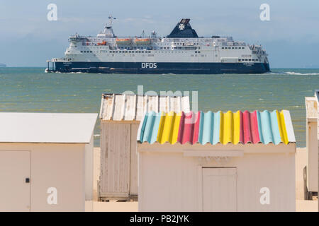 Calais, Frankreich - 19. Juni 2018: Beach Cabins und DFDS Cross Channel Fähre auf dem Weg nach Dover, Großbritannien. Stockfoto