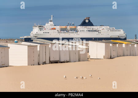 Calais, Frankreich - 19. Juni 2018: Beach Cabins und DFDS Cross Channel Fähre auf dem Weg nach Dover, Großbritannien. Stockfoto