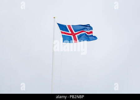 Eine zivile Flagge und Fähnrich Island gegen einen bewölkten Himmel. Die Nationalflagge der Isländer ist blau wie der Himmel mit einem Schnee-weißen Kreuz und eine feurig-r Stockfoto