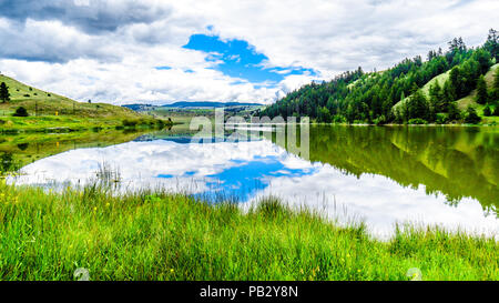 Blauer Himmel, Wolken und die umliegenden Berge im Wasser von Trapp See widerspiegelt, entlang der Autobahn 5 zwischen Kamloops und Merritt im schönen BC Kanada Stockfoto