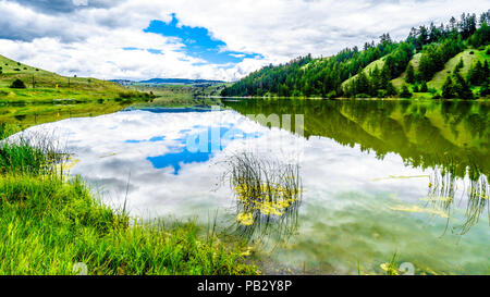 Blauer Himmel, Wolken und die umliegenden Berge im Wasser von Trapp See widerspiegelt, entlang der Autobahn 5 zwischen Kamloops und Merritt im schönen BC Kanada Stockfoto