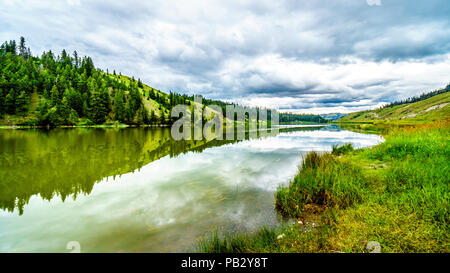 Dunkle Wolken und die umliegenden Berge im Wasser von Trapp See widerspiegelt, entlang der Autobahn 5 zwischen Kamloops und Merritt im schönen BC Kanada Stockfoto