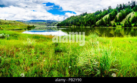 Blauer Himmel, Wolken und die umliegenden Berge im Wasser von Trapp See widerspiegelt, entlang der Autobahn 5 zwischen Kamloops und Merritt im schönen BC Kanada Stockfoto