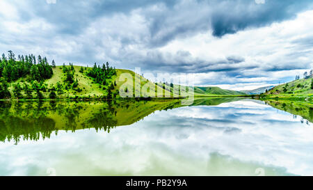 Dunkle Wolken und die umliegenden Berge im Wasser von Trapp See widerspiegelt, entlang der Autobahn 5 zwischen Kamloops und Merritt im schönen BC Kanada Stockfoto