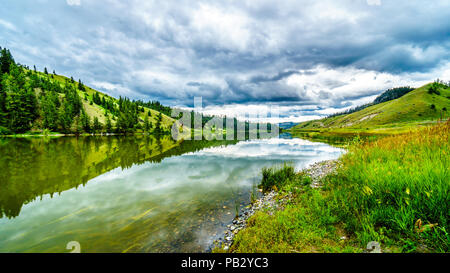 Dunkle Wolken und die umliegenden Berge im Wasser von Trapp See widerspiegelt, entlang der Autobahn 5 zwischen Kamloops und Merritt im schönen BC Kanada Stockfoto