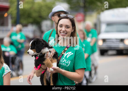 Frankenmuth, Michigan, USA - Juni 10, 2018 junge Frau trägt Ihr Welpe hinunter die Straße an der Bayerischen Festival Parade. Stockfoto