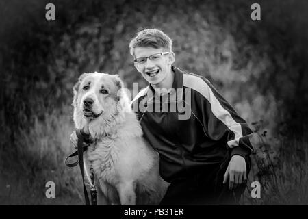 Ein junger Kerl in einem sportanzug in der Natur mit seinem Haustier. Hunderasse Alabai mit seinem Liebling Host. Stockfoto