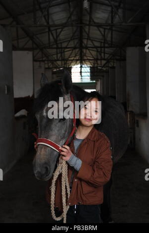 (180726) - NANCHANG, 26. Juli 2018 (Xinhua) - Chen Xinyang, ein Schüler von Sonnenschein Reitschule, dargestellt ist mit einem Pferd in Yihuang Grafschaft von Fuzhou, der ostchinesischen Provinz Jiangxi, 15. März 2018. Pferdesport nie in Yihuang, eine landwirtschaftliche Grafschaft in der ostchinesischen Provinz Jiangxi gehört, bis Sonnenschein Reitschule begann Recruiting ländliche Jugendliche im Jahr 2015. Bisher haben die meisten der 90 Schüler arbeiten oder angehende im Pferd zur Arbeit reiten Vereine in Chinas größten Städten wie Peking, Shanghai und Hangzhou. (Xinhua / Zhou Mi) (lmm) Stockfoto