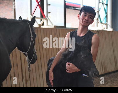 (180726) - NANCHANG, 26. Juli 2018 (Xinhua) - Zhou Jian, ein Schüler von Sonnenschein, Reitschule, hält ein Pony in seine Arme in Yihuang Grafschaft von Fuzhou, East China's Jiangxi Province, 22. Mai 2018. Pferdesport nie in Yihuang, eine landwirtschaftliche Grafschaft in der ostchinesischen Provinz Jiangxi gehört, bis Sonnenschein Reitschule begann Recruiting ländliche Jugendliche im Jahr 2015. Bisher haben die meisten der 90 Schüler arbeiten oder angehende im Pferd zur Arbeit reiten Vereine in Chinas größten Städten wie Peking, Shanghai und Hangzhou. (Xinhua / Zhou Mi) (lmm) Stockfoto