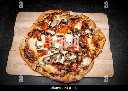 Handgefertigte hausgemachte Pilz und Chorizo Pizza frisch gebackene auf Holzbrett Stockfoto