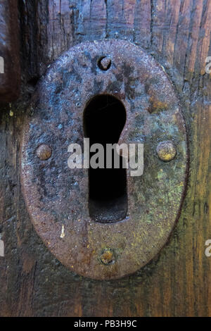Nahaufnahme einer rostigen metallische Schlüsselloch auf einen verschlissenen Holz Tür. Keine Menschen. Stockfoto