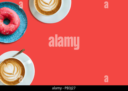 Ansicht von oben. Zwei Tassen duftenden Kaffee Cappuccino und eine Reihe von donut auf einem roten Hintergrund. In der Nähe Platz für Text. Stockfoto