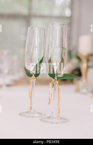 Die Brille der Bräutigam und die Braut mit einem goldenen Bein mit grünen Blättern verziert. Hochzeit Gläser für Sekt Stockfoto