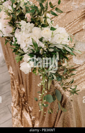 Großes Volumen und Zusammensetzung von wunderschönen Blumen und Grünen. Ein goldenes Tuch auf einen Tisch und Hochzeit Blumen Stockfoto